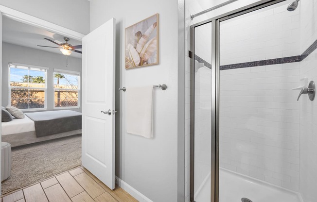 a white bathroom with a shower and a bed in the corner
