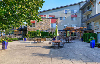 a patio with tables and umbrellas in front of an apartment building at Delano, Washington, 98052