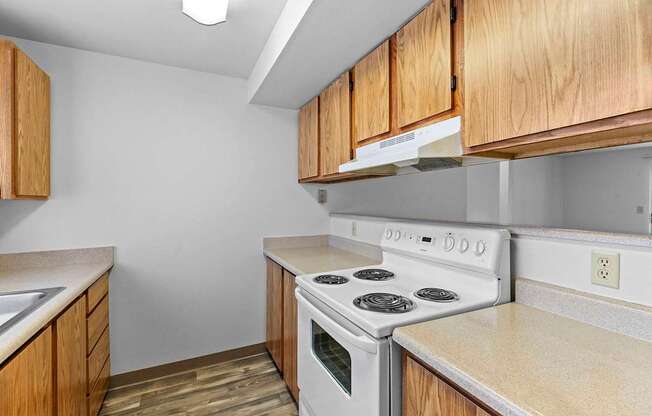 A kitchen with a white stove and wooden cabinets.