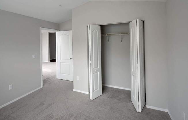 A room with a carpeted floor and two open doors.