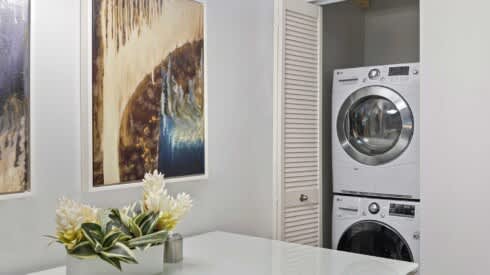 a white laundry room with a washing machine and a sink