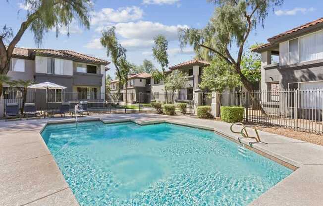 A swimming pool in a residential area surrounded by houses and trees.