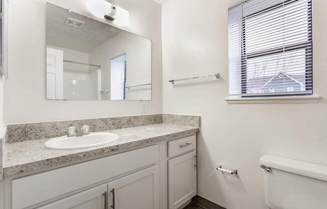 A white bathroom with a sink, mirror, and tub.