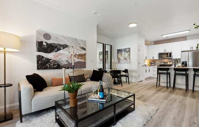 a living room with a couch coffee table and a kitchen in the background