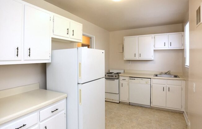 View of kitchen model with white cabinets, refrigerator, dishwasher, range