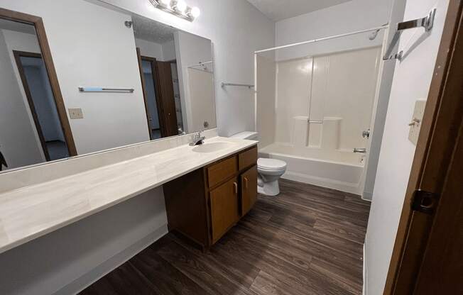 A bathroom with a toilet, sink, and mirror.