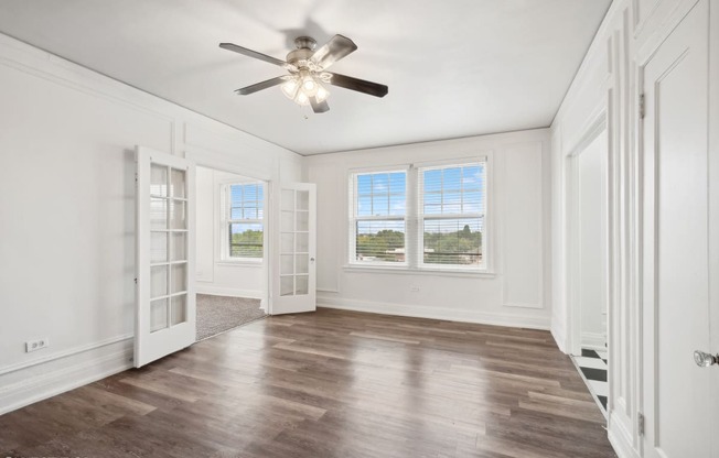 an empty living room with white walls and a ceiling fan at The Embassy in St Louis