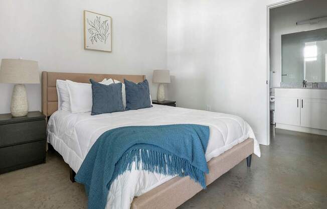 A bedroom with a bed, two lamps, and a framed picture on the wall.
