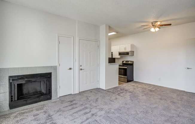an empty living room with a fireplace and a kitchen