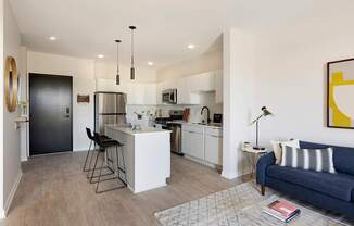 A modern kitchen with a bar stool and a blue sofa.