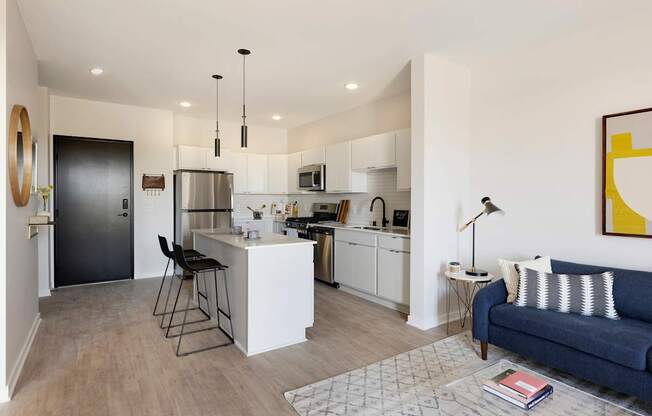A modern kitchen with a bar stool and a blue sofa.