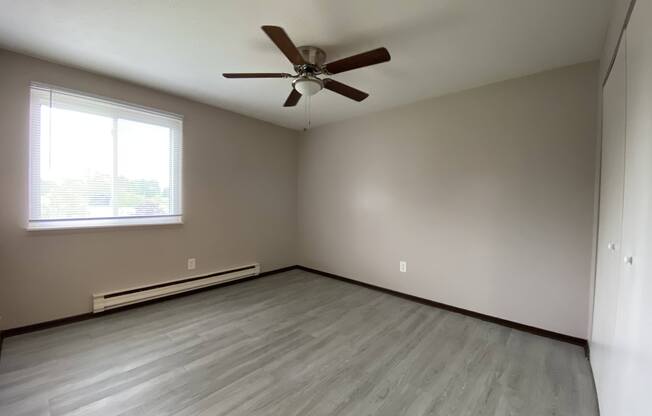 an empty bedroom with vinyl floors and a ceiling fan