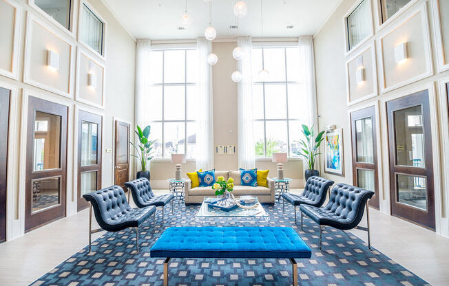 a living room with blue furniture and tall windows