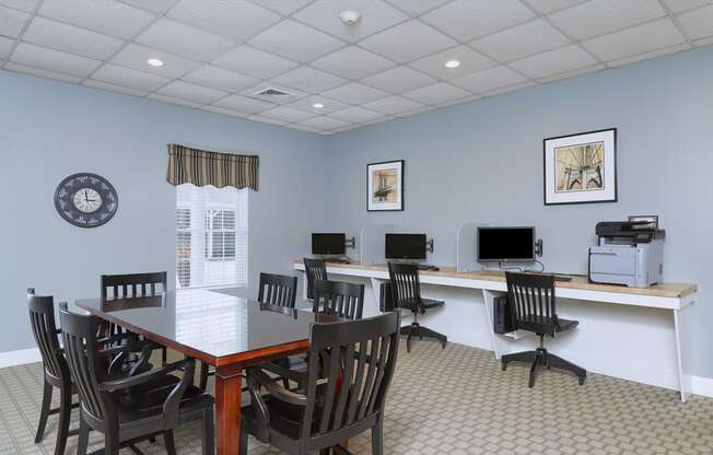 a conference room with a table and chairs and a desk with computers