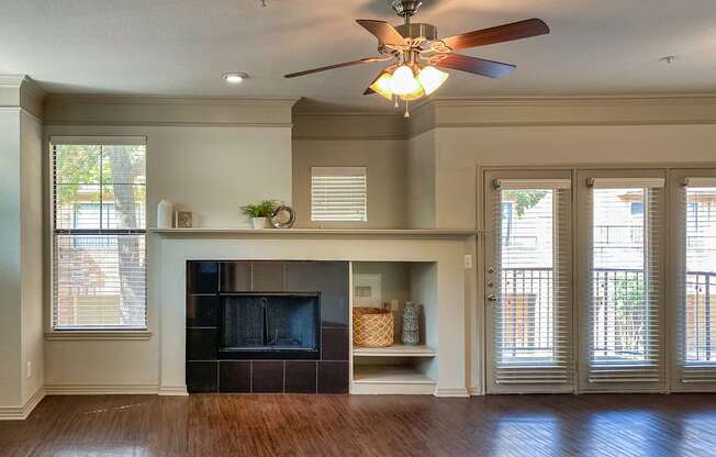 Living room in the 1486-square-foot 3-bedroom, 3-bath apartment with attached 2-car garage at The Brownstones in Far North Dallas, Texas, featuring a fireplace with an extended mantel ledge and built-in storage niche