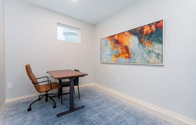 A room with a table and chairs and a painting on the wall.