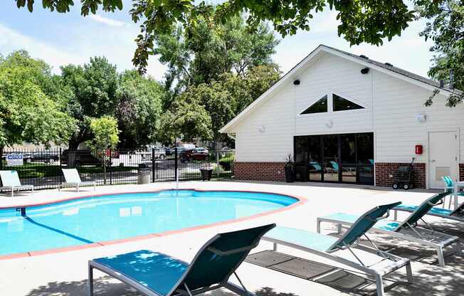 A pool with lounge chairs and a white building in the background.