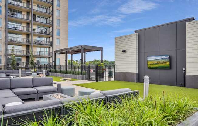 a grassy area with couches and a fire pit in front of an apartment building