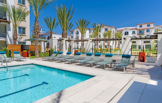 A swimming pool surrounded by palm trees and lounge chairs.