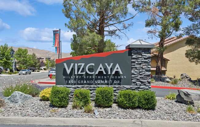 A sign for Vizcaya Hilltop Apartment Homes stands in front of a building.
