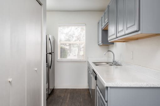 an empty kitchen with white countertops and a window