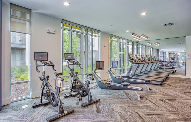 a gym with rows of exercise bikes and windows at Presidium Revelstoke, Fort Worth