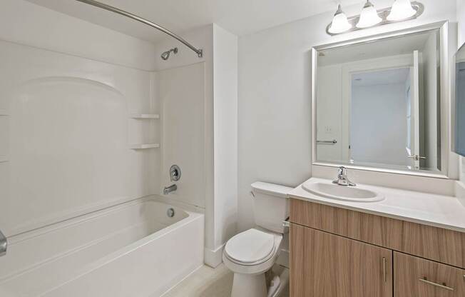 A white bathroom with a tub, toilet, sink, and mirror.