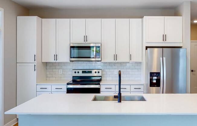 a kitchen with white cabinets and stainless steel appliances