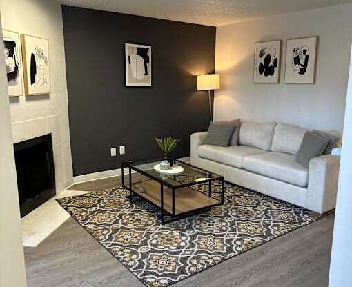 A living room with a grey couch, a coffee table, and a fireplace.