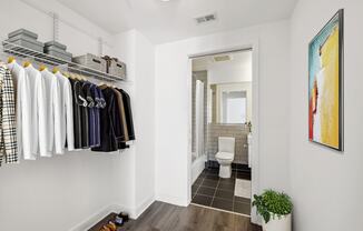 a closet with clothes and a bathroom with a toilet
