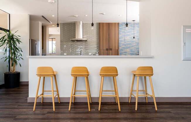 Three wooden bar stools are placed in front of a bar.