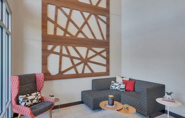 A living room with a grey couch, a red chair and a wooden wall panel.