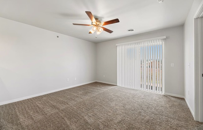 an empty living room with a ceiling fan and a window