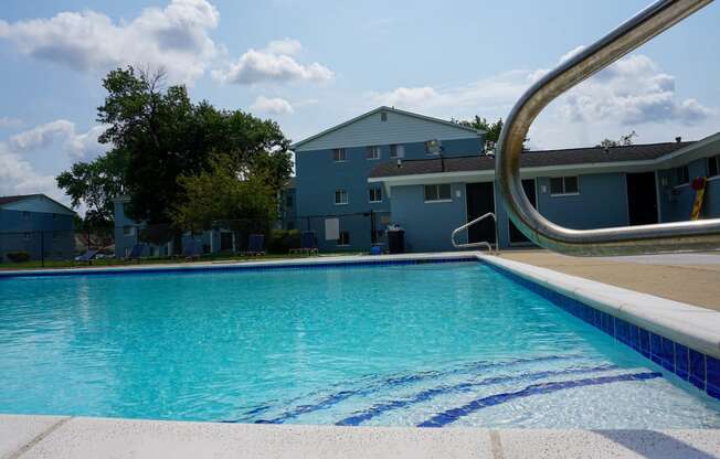 Swimming Pool Entry with pool chairs and apartment building, at Gale Gardens