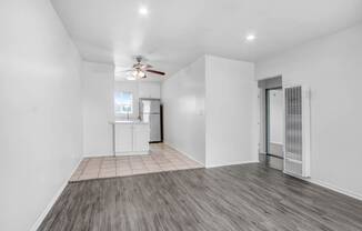 an empty living room with white walls and a ceiling fan