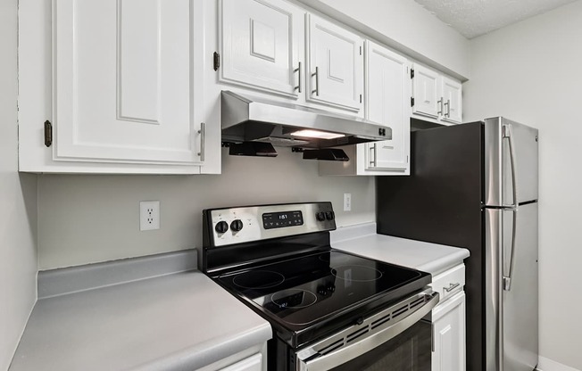 A kitchen with white cabinets and a black refrigerator.