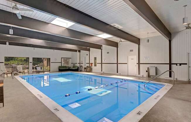 a large indoor swimming pool in a white building with a ceiling with skylights
