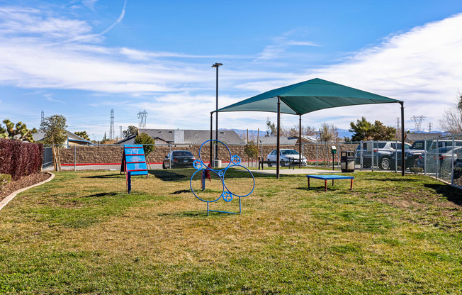 a playground with a green canopy and a blue bench
