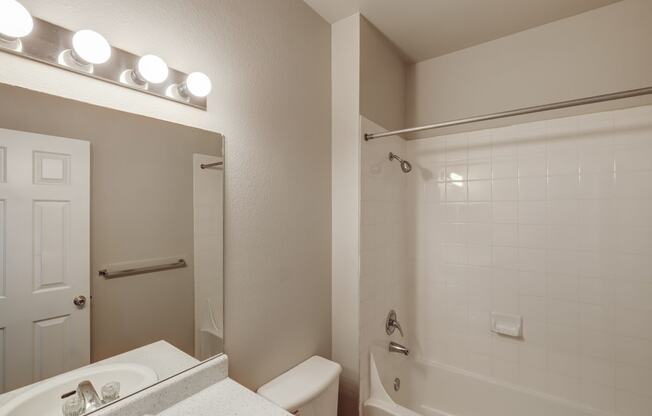 a bathroom with a white tub and a sink and a mirror