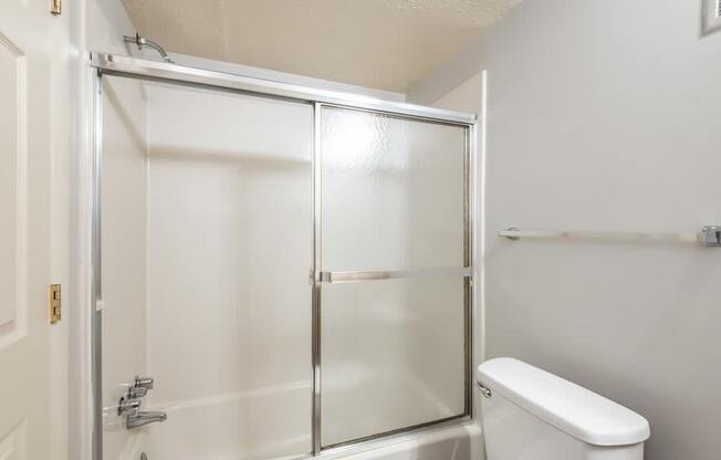 A white toilet sits next to a glass shower door in a bathroom.