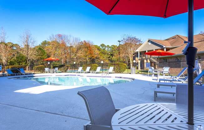 a pool with chairs and umbrellas next to a house