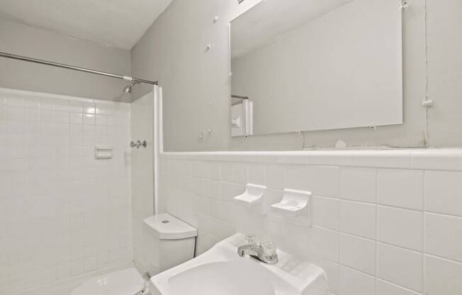 a white bathroom with a sink and a mirror and a toilet