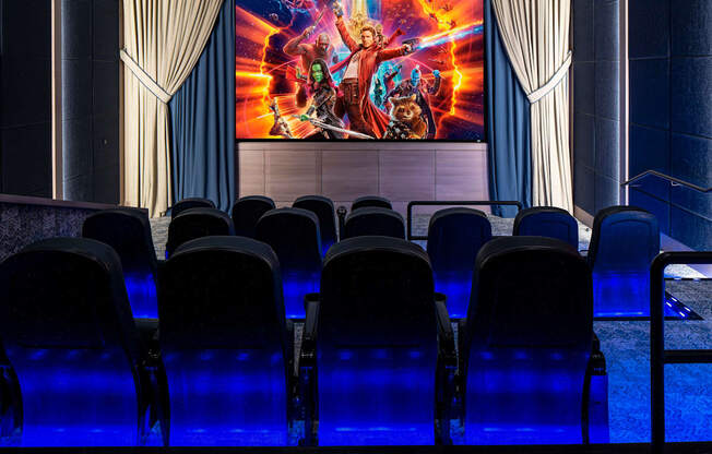 a theater with blue chairs and a large movie screen on the wall