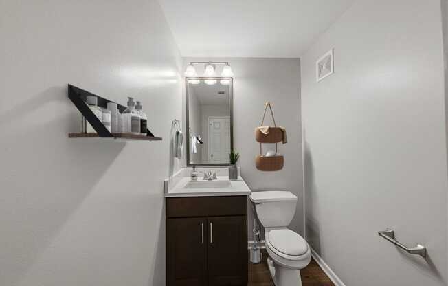 A bathroom with a toilet, sink, and mirror.