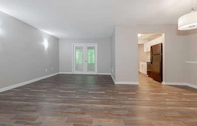 A room with a wooden floor and a door leading to another room.