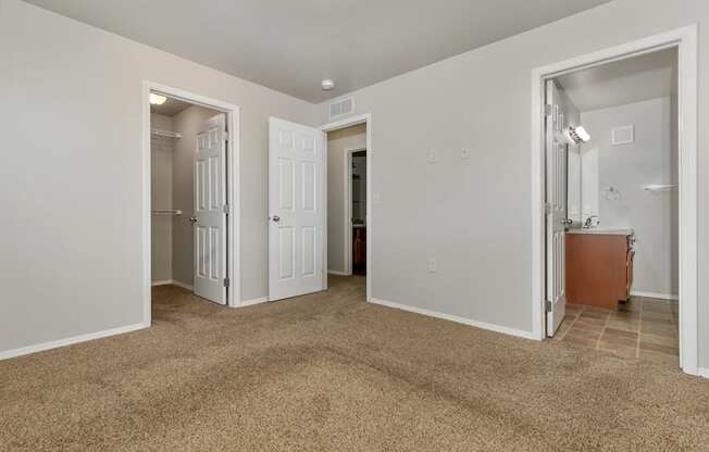 A room with carpeted floor and white walls with a doorway leading to another room.