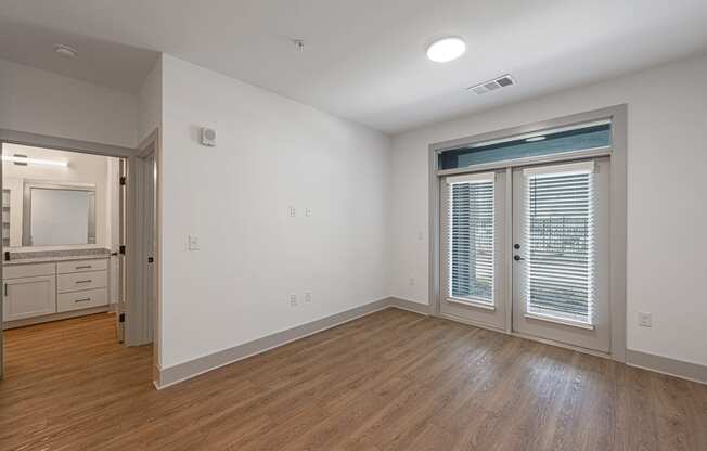 an empty living room with white walls and a door to a bathroom