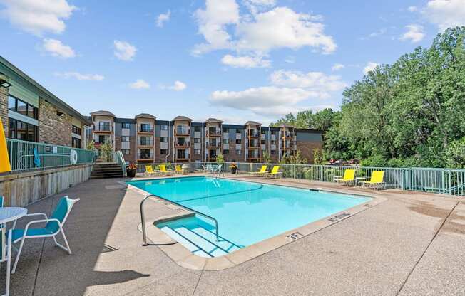 A swimming pool surrounded by chairs and buildings.