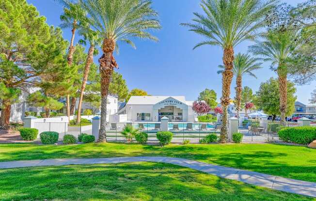 a garden with palm trees and a building in the background