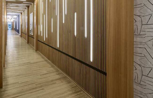 A long hallway with wood paneling and lighting on the ceiling.